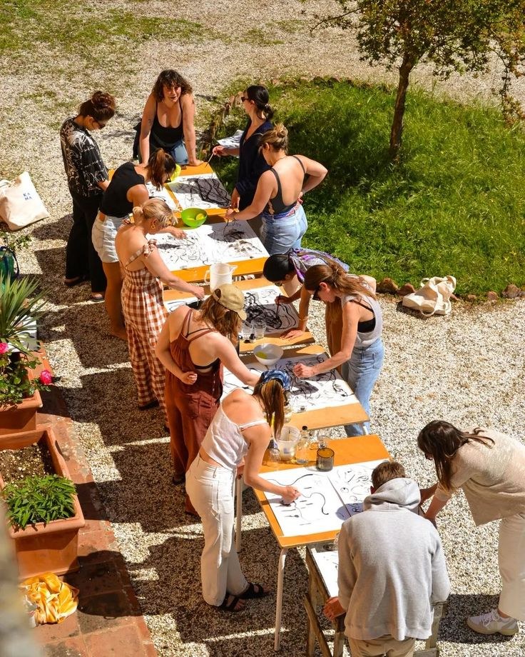 Lunga tavolata all'aperto con persone che partecipano a un laboratorio