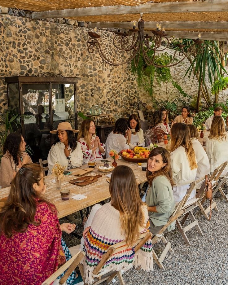 Gruppo di persone sedute insieme attorno a un lungo tavolo in un cortile all'aperto